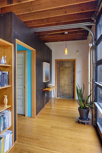 Celery - entry featuring salvaged metal door and inserted volume with restrooms and storage